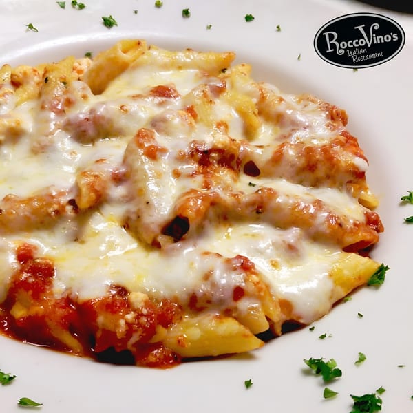 Baked penne pasta with melted mozzarella cheese and red sauce, garnished with parsley.