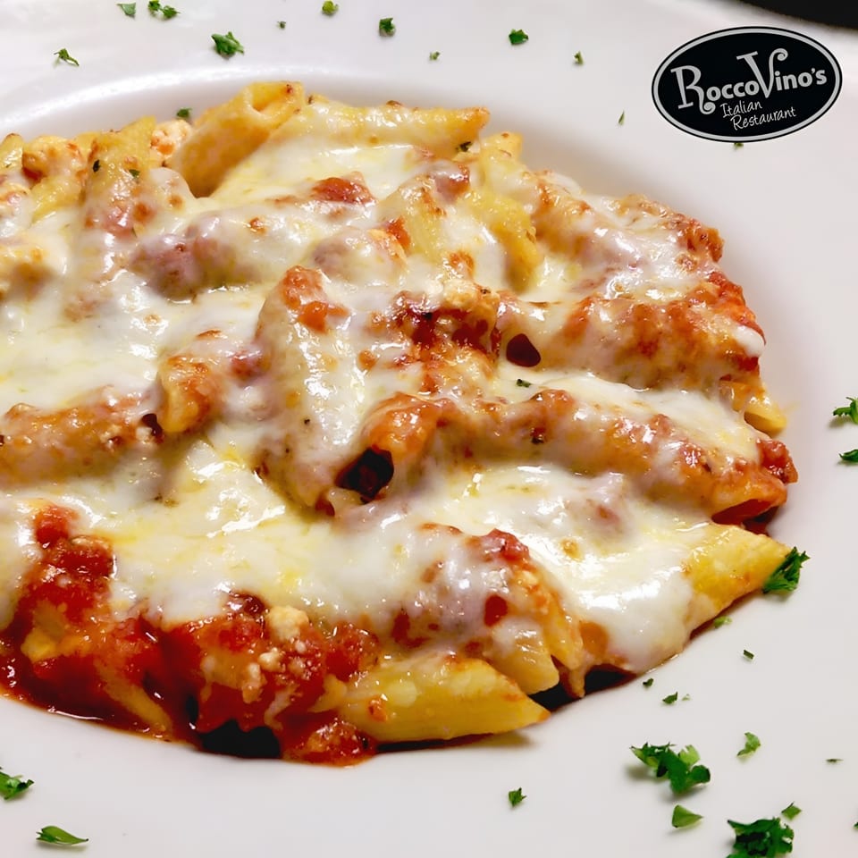 Baked penne pasta with melted mozzarella cheese and red sauce, garnished with parsley.