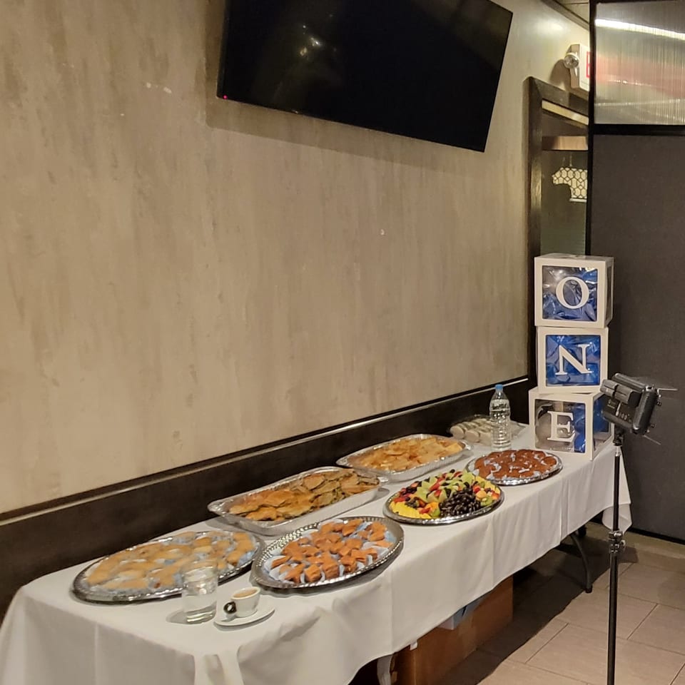 Buffet table with various appetizers, fruit, and desserts, with "ONE" blocks in the background.