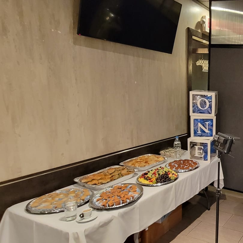 Buffet table with various appetizers, fruit, and desserts, with "ONE" blocks in the background.